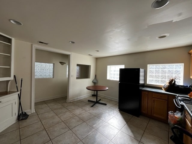 kitchen featuring stove, black fridge, and light tile patterned floors