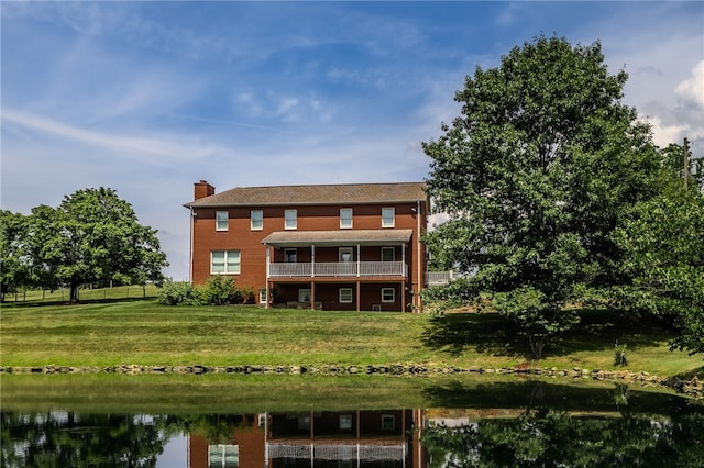 rear view of house with a water view and a yard