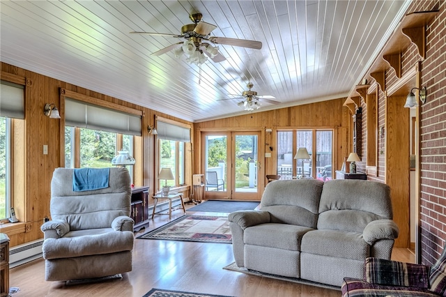 living room featuring light hardwood / wood-style floors, vaulted ceiling, a healthy amount of sunlight, and wooden walls