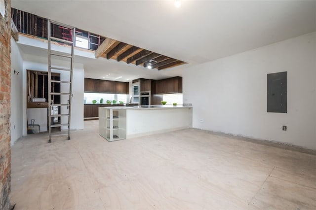 interior space with electric panel, a wealth of natural light, dark brown cabinetry, and kitchen peninsula