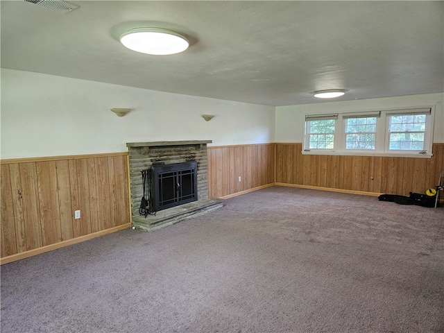 unfurnished living room featuring wood walls, carpet floors, a textured ceiling, and a fireplace