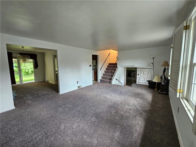 unfurnished living room with dark carpet and a healthy amount of sunlight