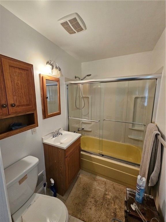 full bathroom featuring vanity, bath / shower combo with glass door, and toilet