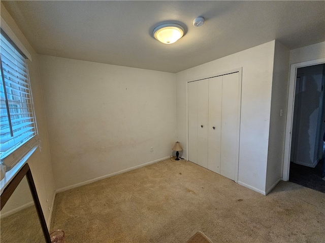 unfurnished bedroom with a closet and light colored carpet