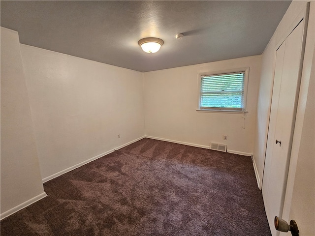 carpeted empty room featuring a textured ceiling