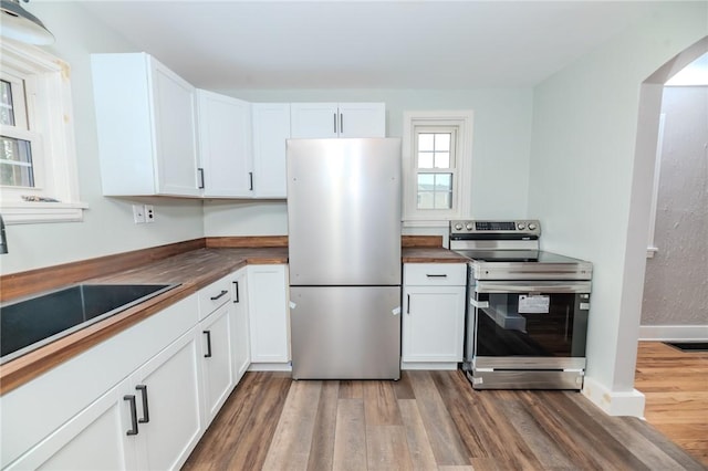 kitchen with appliances with stainless steel finishes, sink, wood-type flooring, and white cabinets