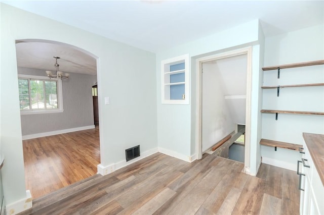 empty room featuring a chandelier and light wood-type flooring