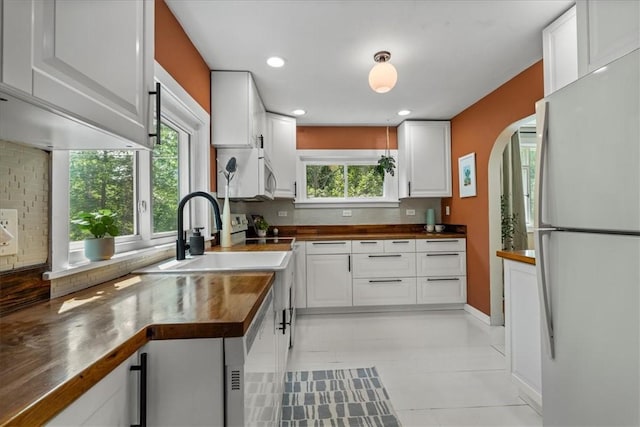 kitchen with butcher block counters, sink, white cabinets, decorative backsplash, and white appliances