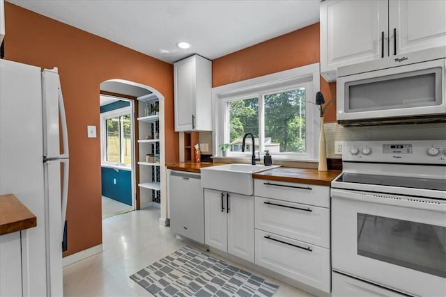 kitchen with wood counters, sink, plenty of natural light, white appliances, and white cabinets