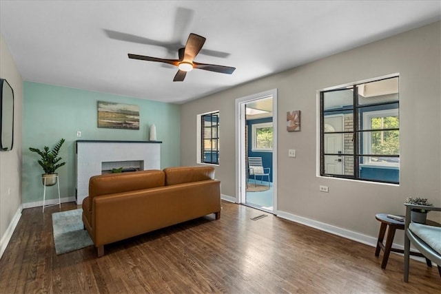 living room featuring a brick fireplace, dark hardwood / wood-style floors, and ceiling fan