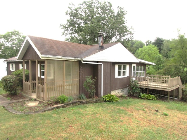 back of house with a deck and a lawn