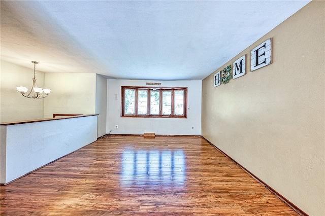 unfurnished room with hardwood / wood-style flooring and a notable chandelier