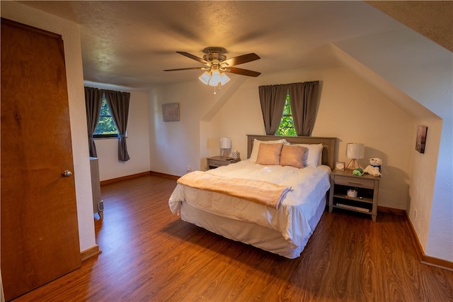 bedroom with ceiling fan, dark hardwood / wood-style floors, vaulted ceiling, and multiple windows