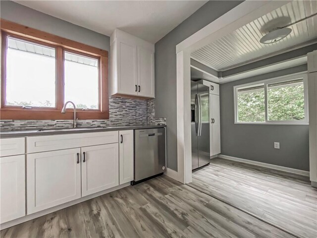 kitchen featuring appliances with stainless steel finishes, light hardwood / wood-style flooring, sink, backsplash, and white cabinetry