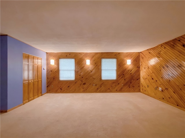 carpeted spare room featuring wooden walls