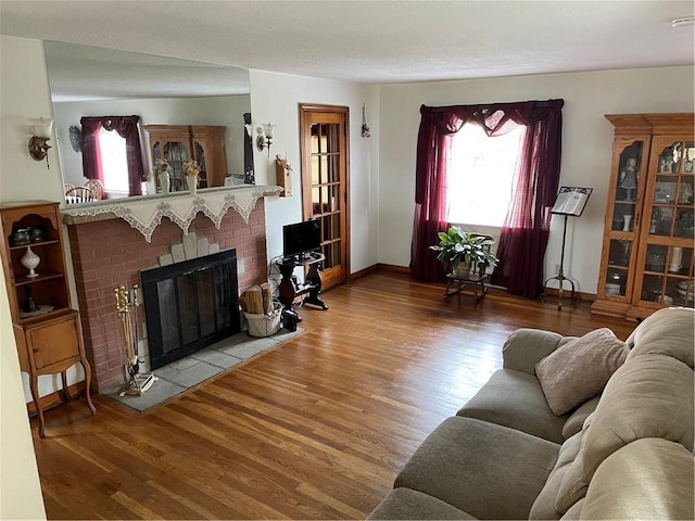 living room with a brick fireplace and wood-type flooring