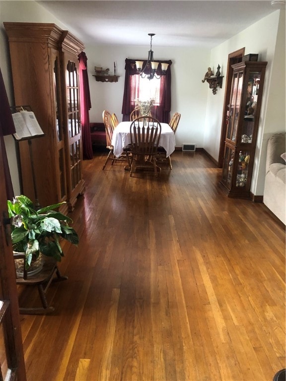 dining space with wood-type flooring and a notable chandelier