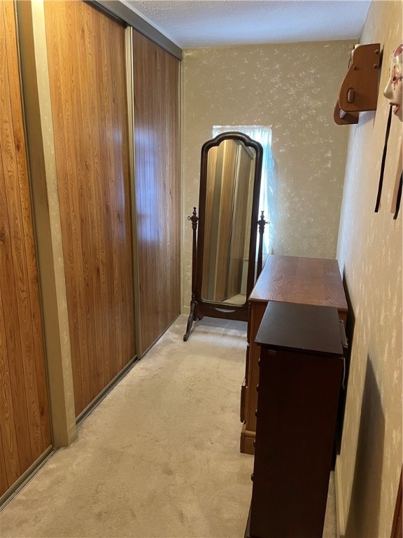 hallway with light carpet and wooden walls