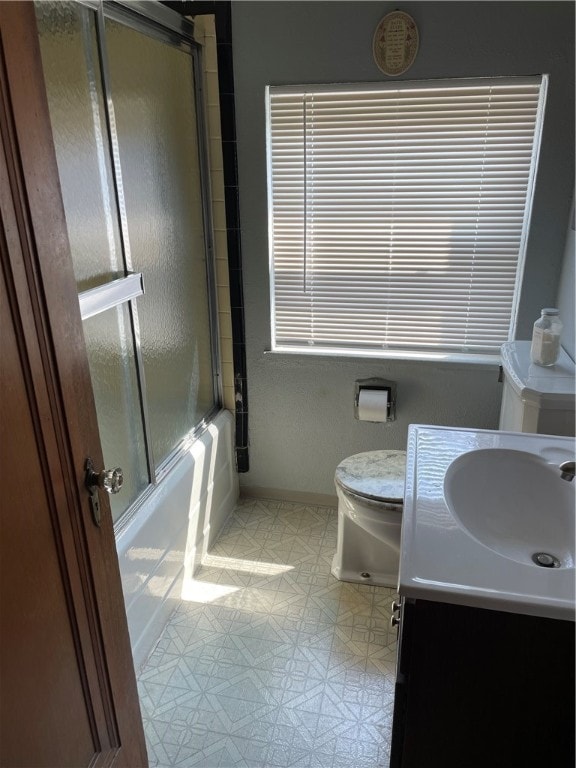 full bathroom featuring tile patterned floors, shower / bath combination with glass door, toilet, and vanity