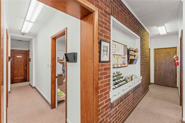 hallway featuring brick wall and light carpet