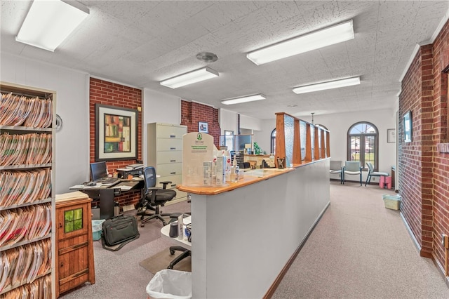 home office with light carpet and brick wall