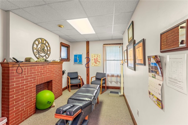 workout room featuring carpet, a brick fireplace, and a paneled ceiling