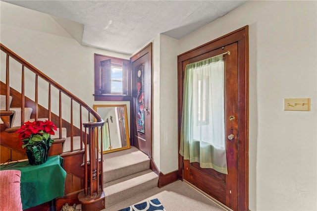 foyer entrance with carpet floors and a textured ceiling