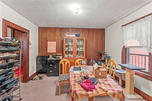 dining space featuring wood walls, light colored carpet, and a textured ceiling