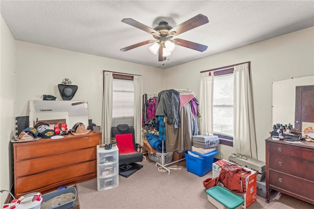 interior space with a textured ceiling, light colored carpet, and ceiling fan