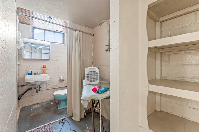 bathroom featuring sink, toilet, and concrete flooring