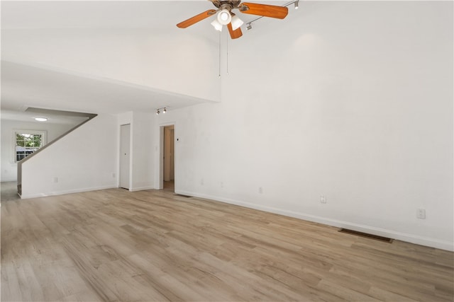 unfurnished living room with light hardwood / wood-style floors, ceiling fan, and high vaulted ceiling