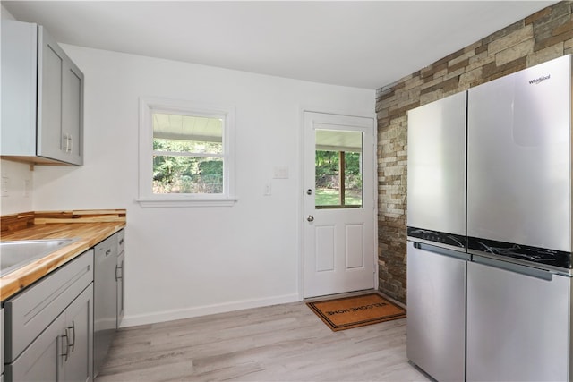 kitchen featuring gray cabinets, light hardwood / wood-style flooring, stainless steel refrigerator, and butcher block counters