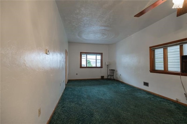 carpeted spare room featuring a textured ceiling and ceiling fan