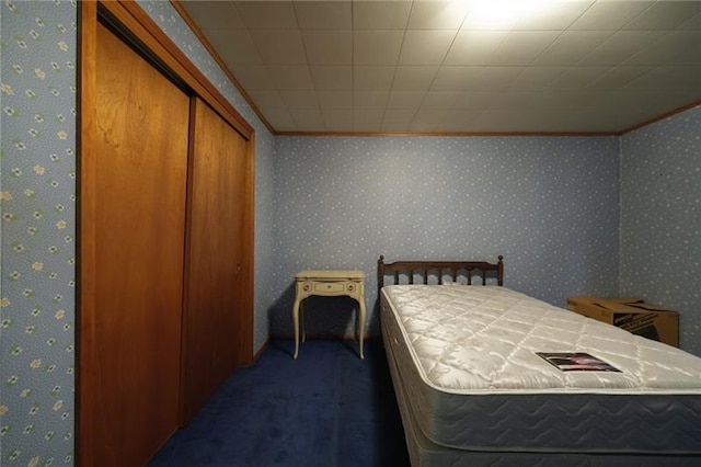 carpeted bedroom with crown molding and a closet