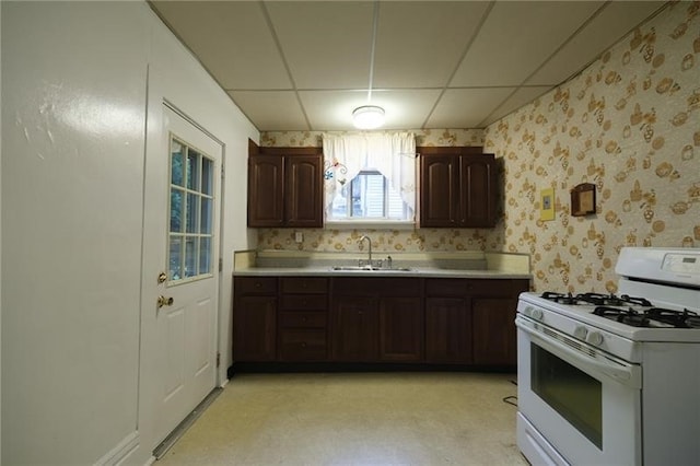 kitchen with sink, dark brown cabinets, white gas range, and a paneled ceiling