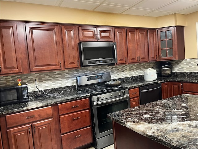 kitchen with dark stone counters, a drop ceiling, black appliances, and tasteful backsplash