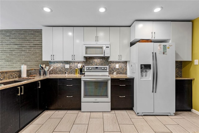 kitchen with dark brown cabinetry, decorative backsplash, white cabinets, and white appliances