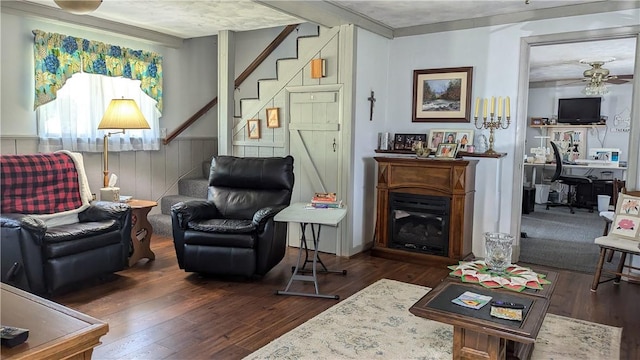 sitting room with dark wood-style floors, stairway, a fireplace, and a ceiling fan