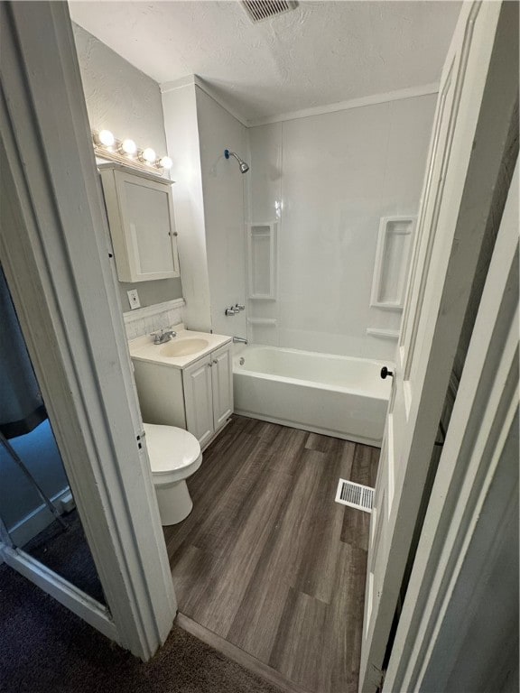 full bathroom with a textured ceiling, bathtub / shower combination, toilet, vanity, and hardwood / wood-style flooring