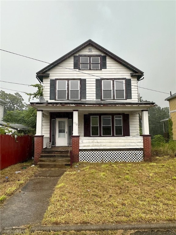 front facade with a front yard and covered porch