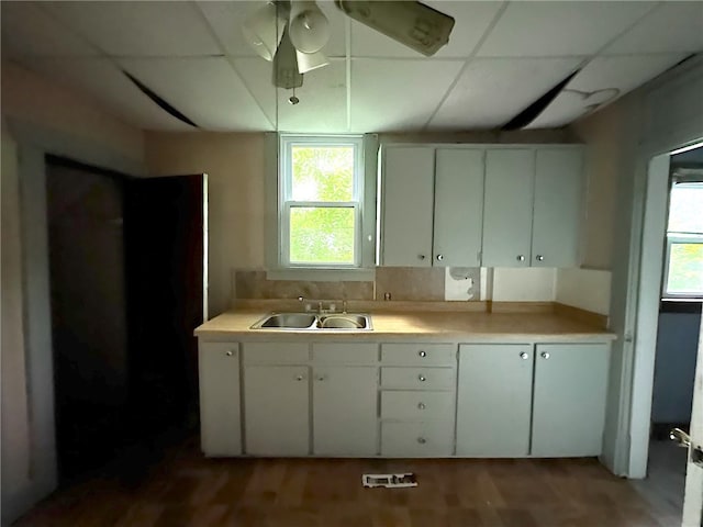 kitchen with a drop ceiling, ceiling fan, white cabinets, sink, and light hardwood / wood-style flooring