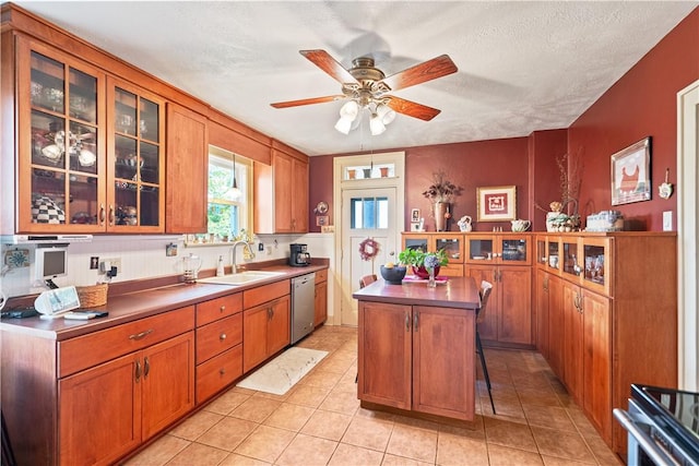 kitchen featuring a kitchen island, glass insert cabinets, dishwasher, light tile patterned floors, and a sink