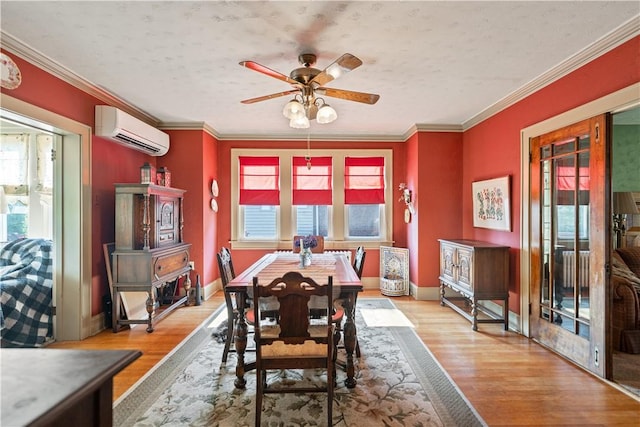 dining room featuring an AC wall unit, wood finished floors, baseboards, and ornamental molding