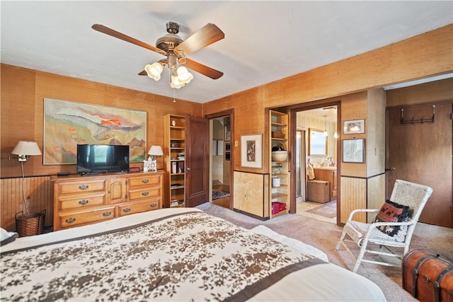 bedroom featuring wooden walls, a ceiling fan, and carpet flooring