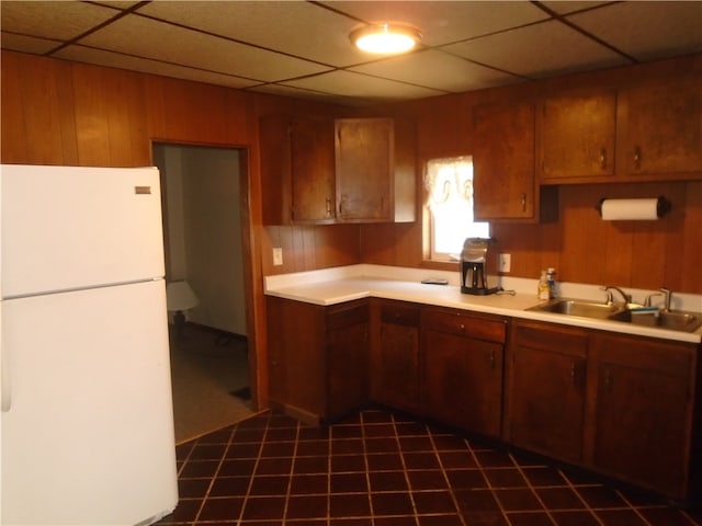 kitchen with sink, dark tile patterned floors, white refrigerator, and a paneled ceiling