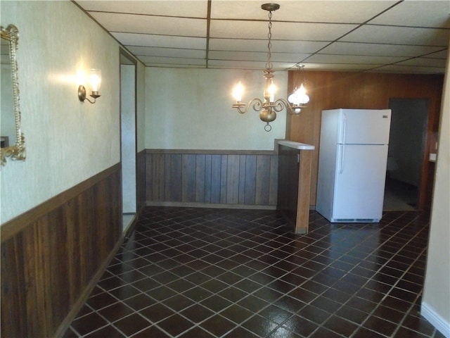 unfurnished dining area featuring a drop ceiling and dark tile patterned floors