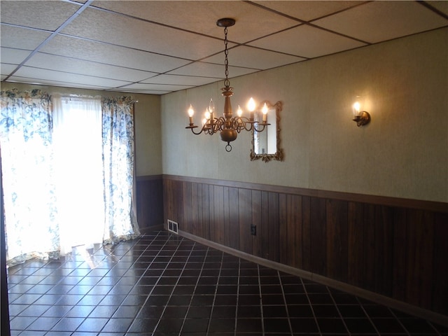 unfurnished room featuring an inviting chandelier, a paneled ceiling, and tile patterned floors