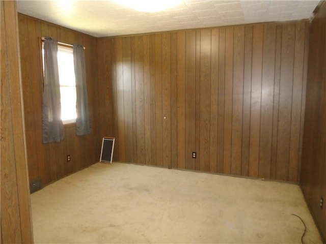 carpeted spare room featuring wooden walls