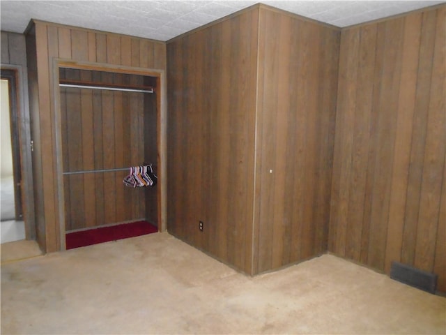 unfurnished bedroom featuring carpet floors, wooden walls, and a closet