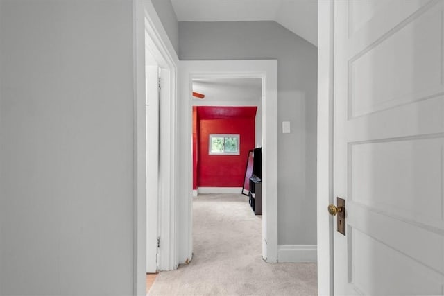 hallway featuring vaulted ceiling and light colored carpet